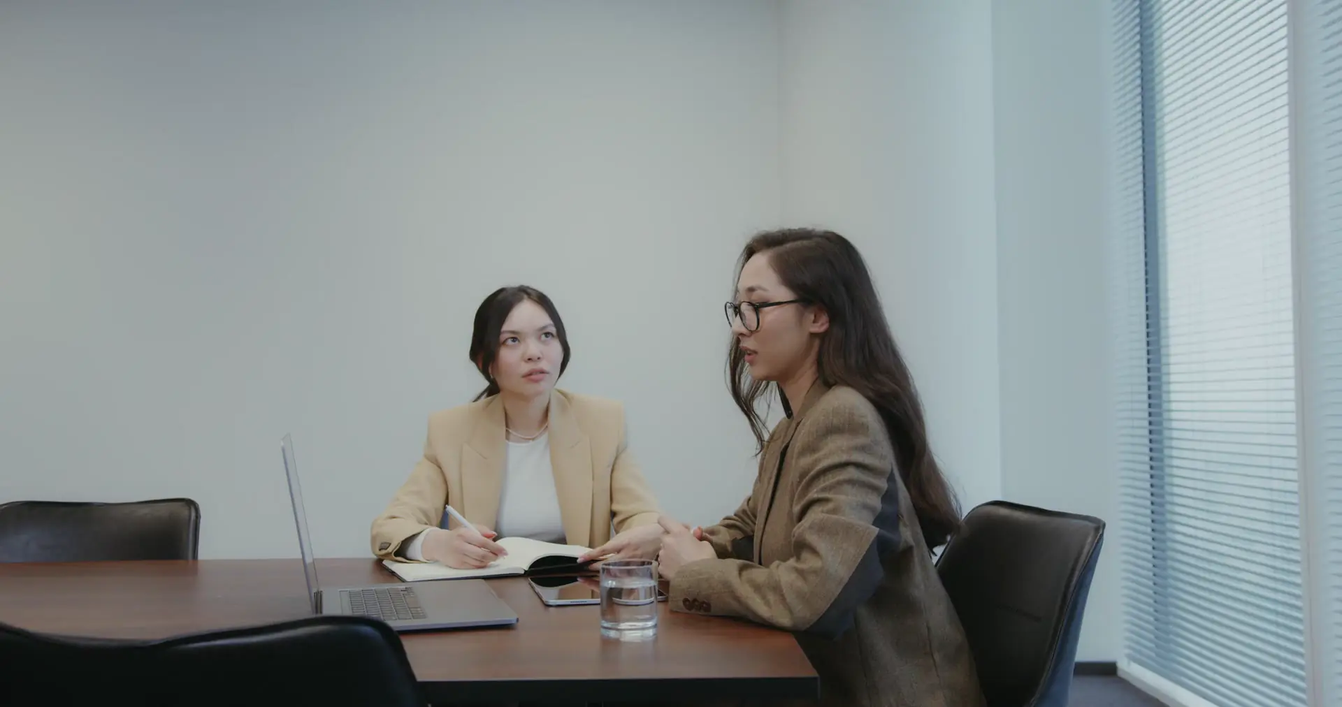 Two women going through papers together at an office table.