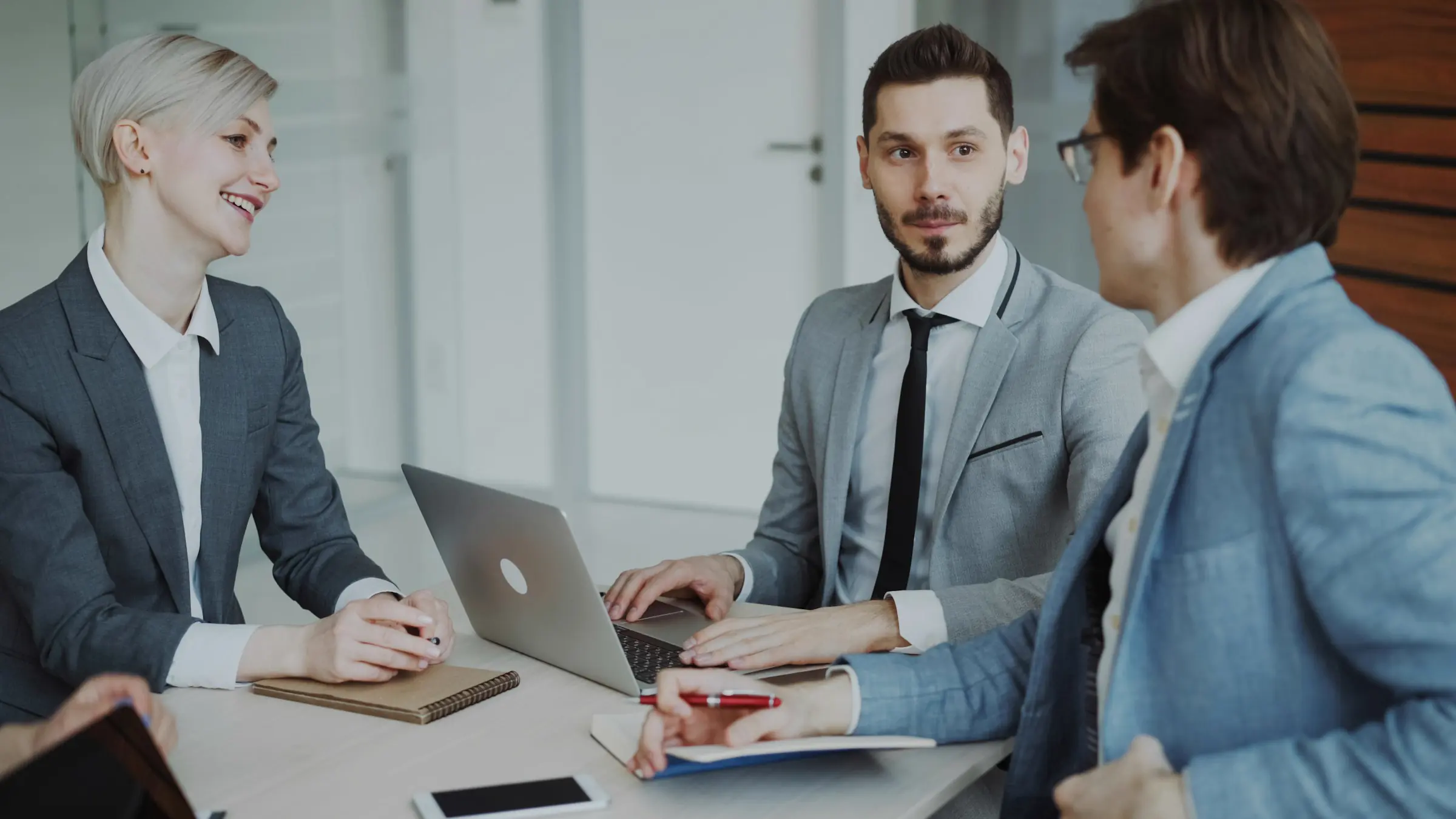 A hiring team of three talks through a role brief at a shared table.